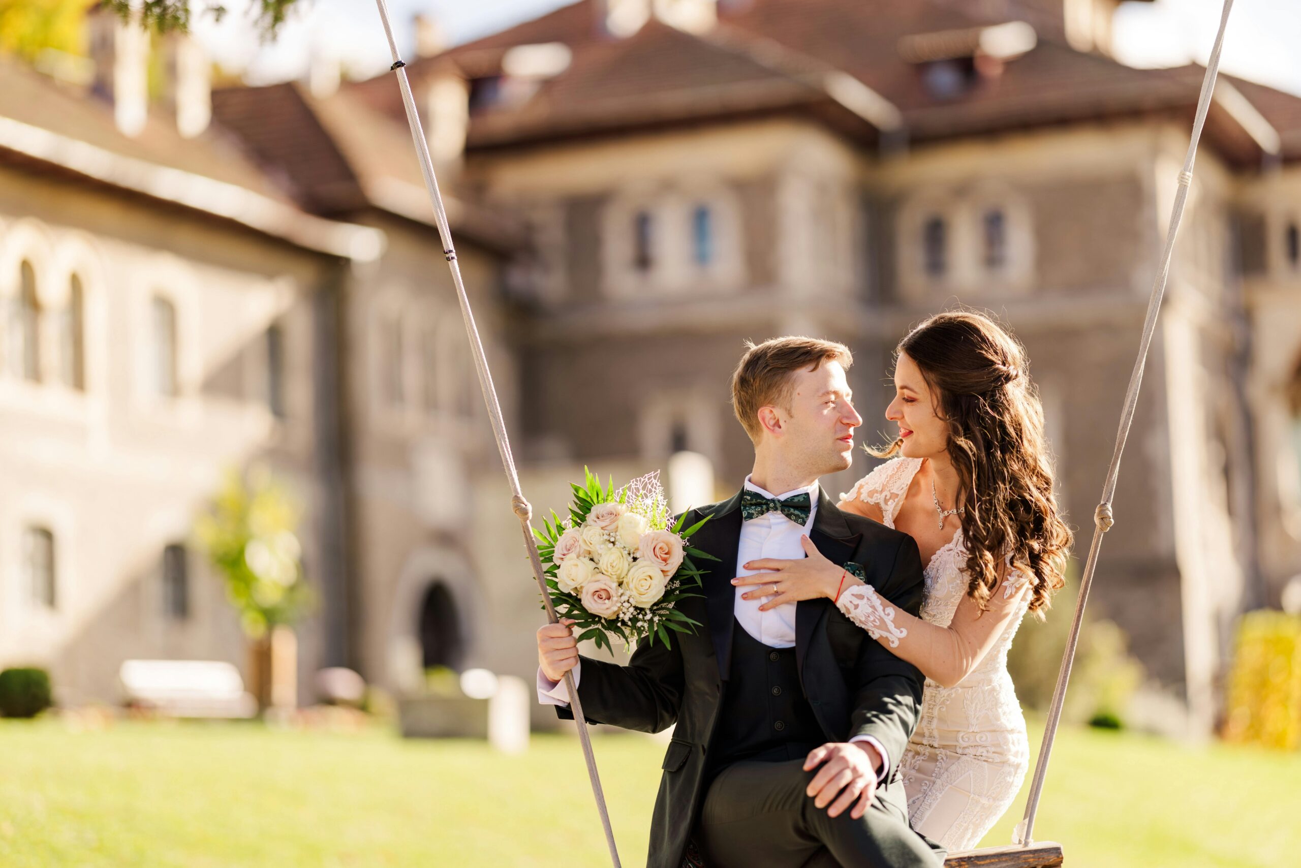 Wedding couple sitting on a swing in front of a old building